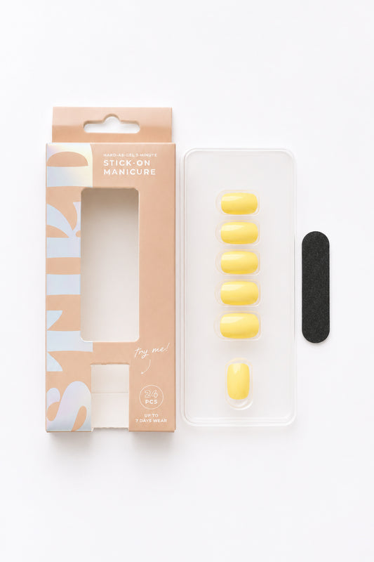 Buttercup pastel yellow press-on nails by STIKD, box opened with nail tray and mini file